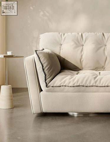 Cream-colored swivel snuggle chair with dark piping and sleek metallic base in beige for cozy seating