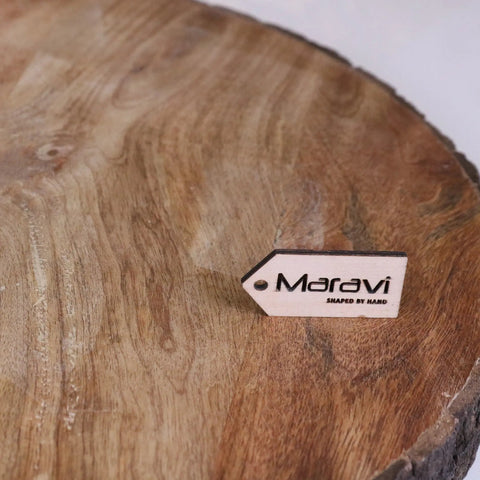 White rectangular wooden tag with black maravi shaped by hand text for bhimra round wooden chopping board bark edge 42cm