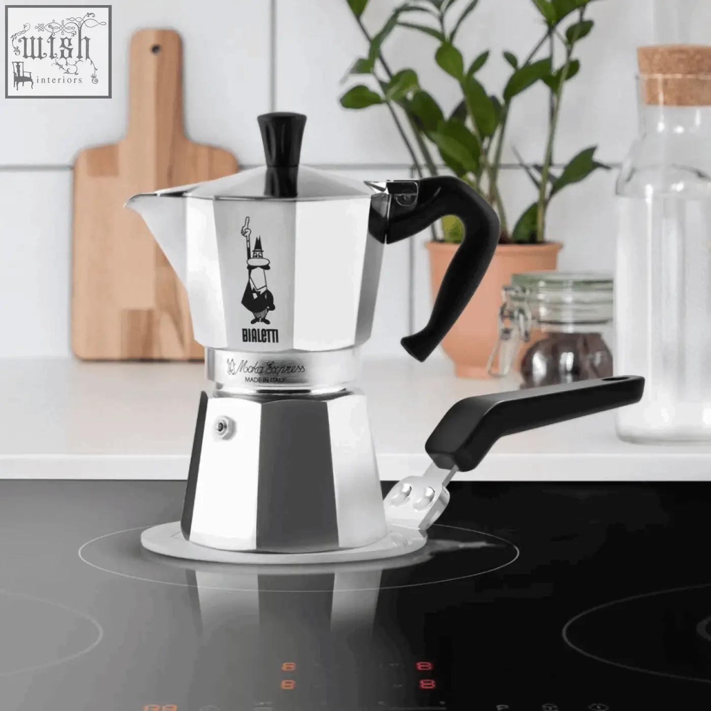 Silver bialetti moka express stovetop coffee maker with black handles and classic logo on bialetti induction plate