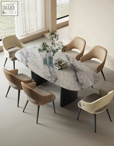Modern oval dining table with white marble top gray veining and black pedestal legs paired with bianchi leather dining chairs offer style for your dining room