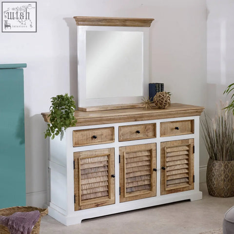 White and natural wood console table with louvered doors and black knobs below bianco solid mango wood wall mirror