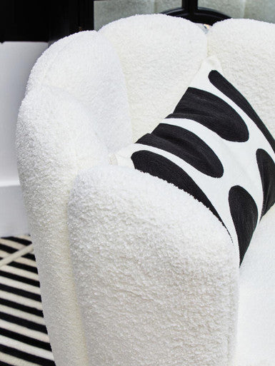White boucle scalloped swivel chair with plush towel shape and black and white abstract cushion in its curves