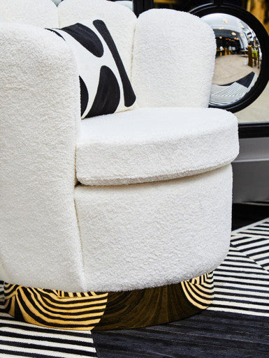 White boucle scalloped swivel chair with plush tufted upholstery and black and white abstract pillow