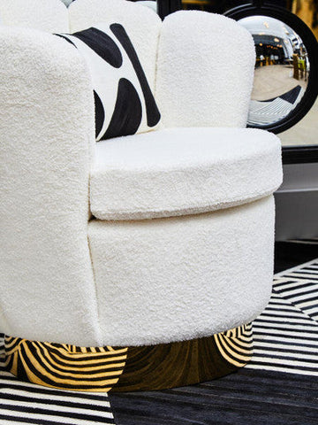 White boucle scalloped swivel chair with plush tufted upholstery and black and white abstract pillow