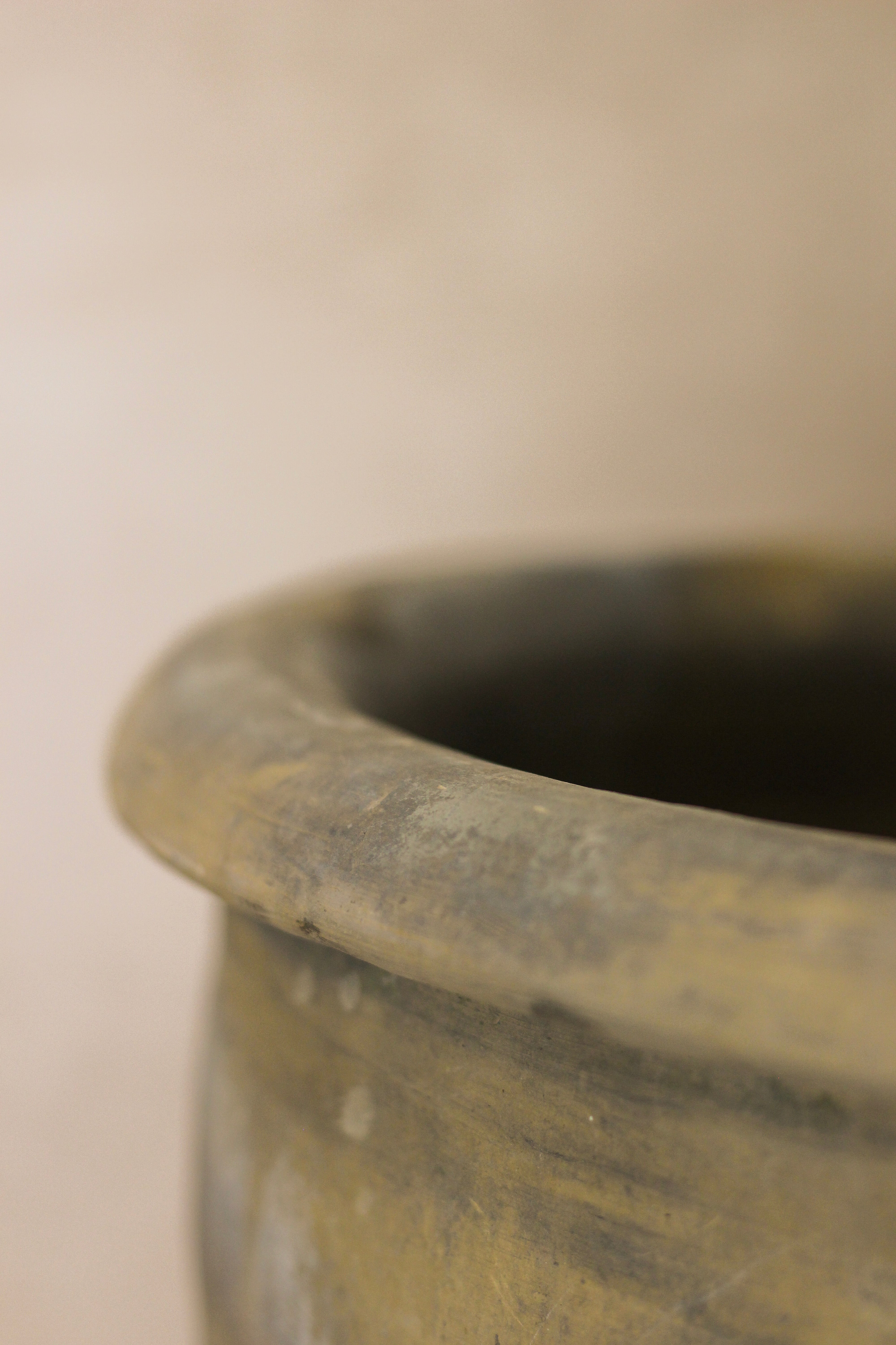 A weathered grey asian ceramic pot with earth tones and a slightly chipped rim perfect for rustic decor