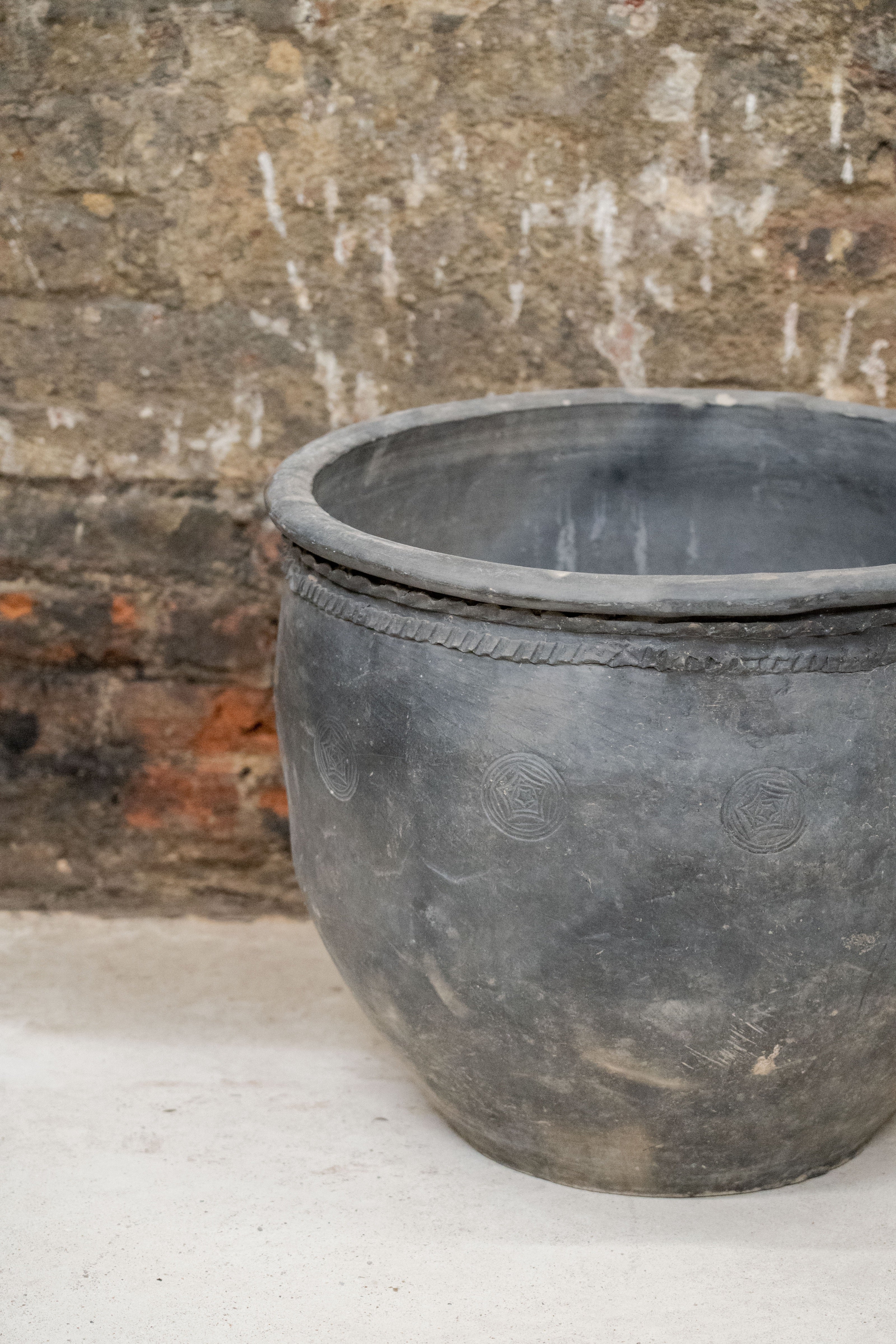 Big old grey asian pot dark gray weathered ceramic planter with embossed circles and rope band around the rim