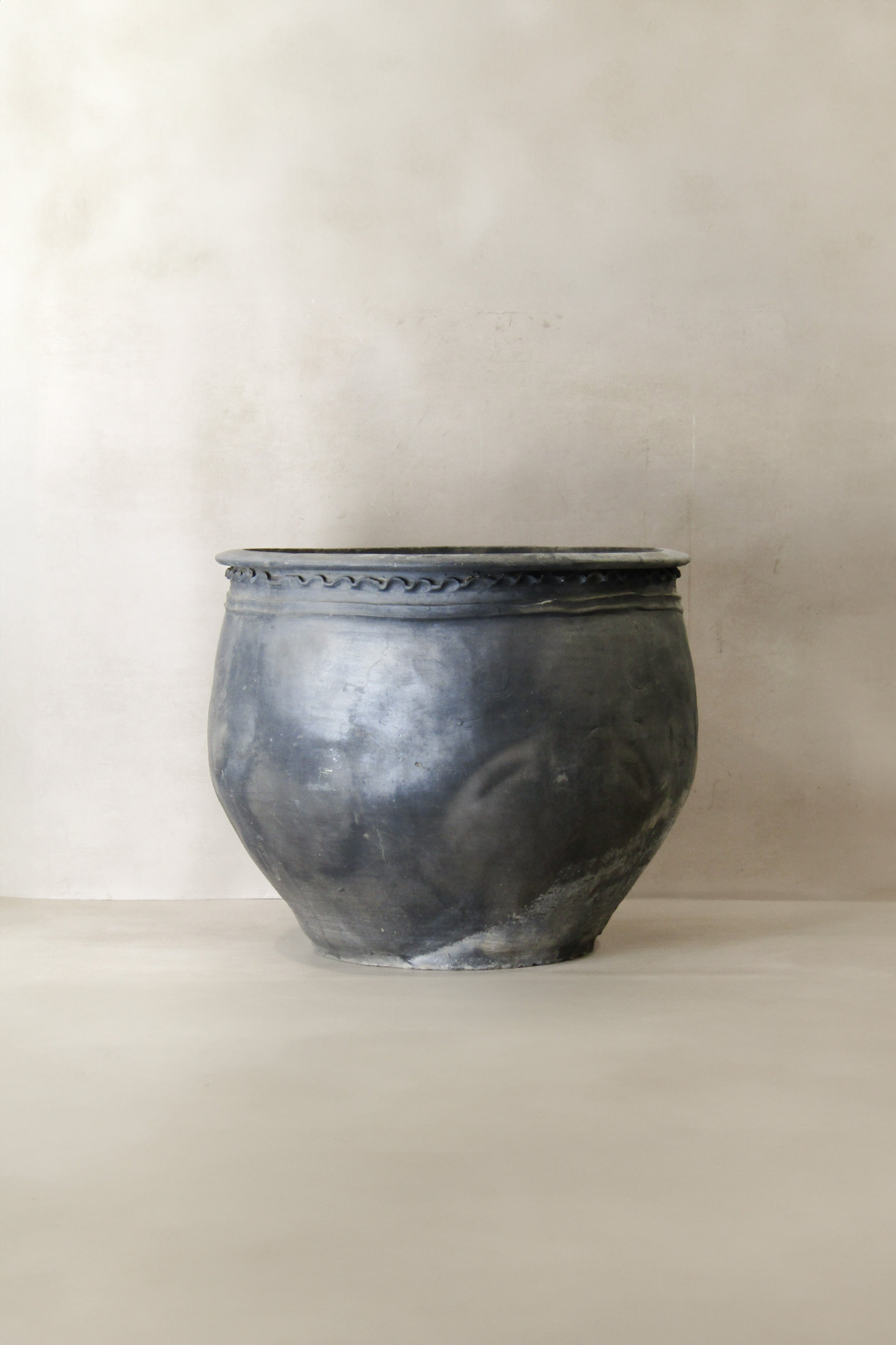A matte-finished dark gray ceramic planter with textured surface and wavy rim from big old grey asian pots collection