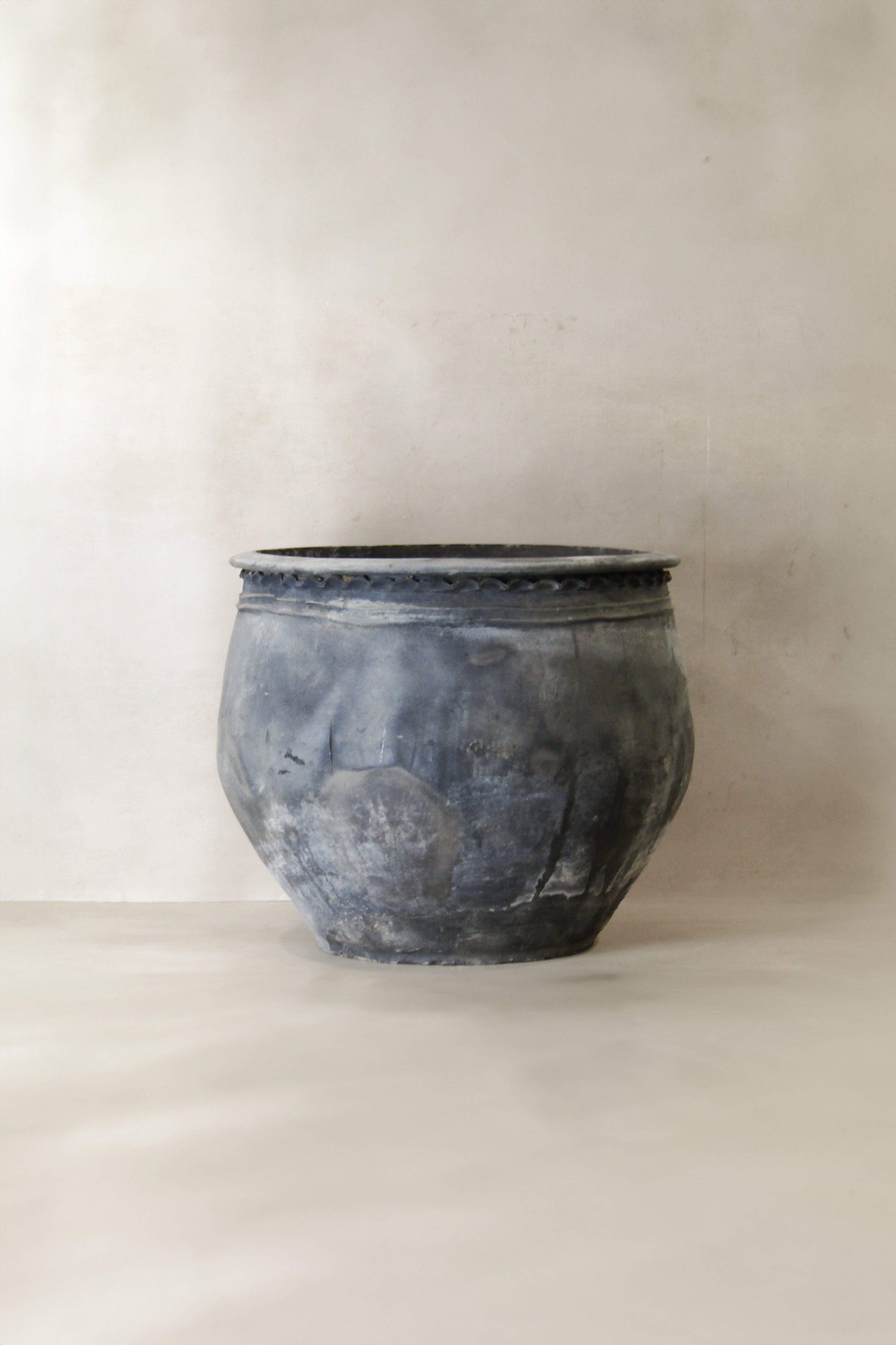 A weathered dark gray metal planter with textured surface and beaded rim from big old grey asian pots l020