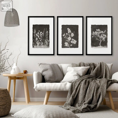 Three black-framed french country wall art prints with white wildflower silhouettes on dark backgrounds for living room