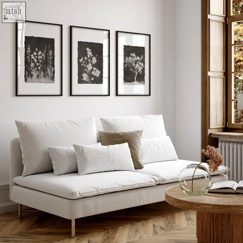 White upholstered sofa with metallic legs and cushions in living room featuring french country dark floral wall art set of 3