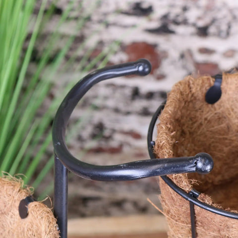 Black metal bike garden planter with curved hooks holding brown coconut fiber pot for rustic garden decor