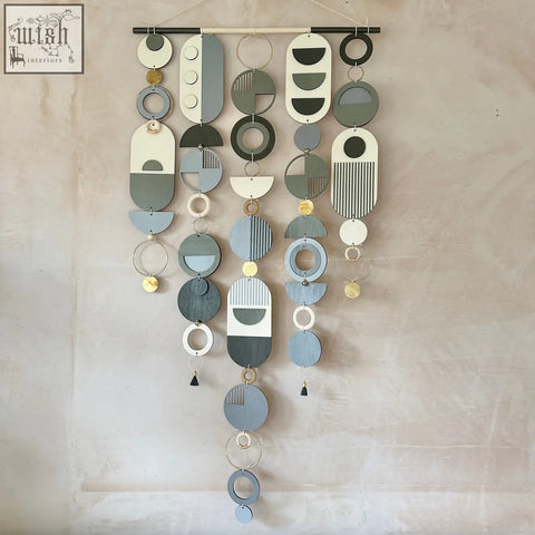 A modern geometric hand painted wall art with layered wooden discs in muted blues grey and white abstract patterns