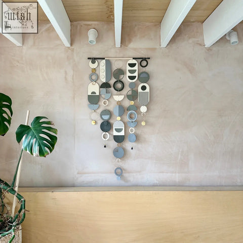 A modern hand painted wall art featuring layered circular and oval shapes in muted greys and metallic accents