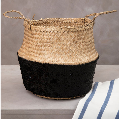 A natural medium seagrass basket with a black sequined lower half and braided handles perfect for stylish storage