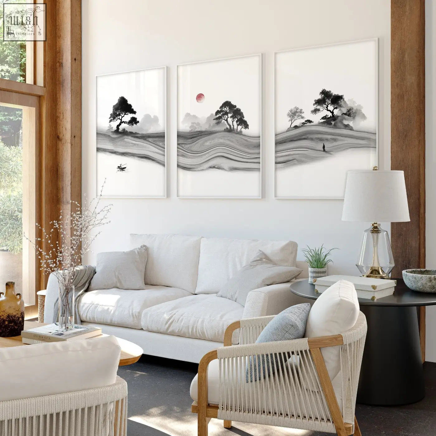 Three black and white ink landscape prints with a red moon mounted above a sofa in a modern living room setting