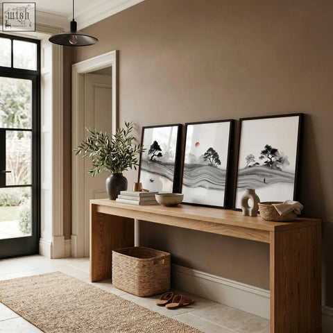 Three framed black and white prints japandi ink landscape with minimalist trees mountains and a red sun on wood table