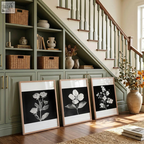 Three black framed botanical floral wall art prints with black and white illustrations in light wood frames and white matting