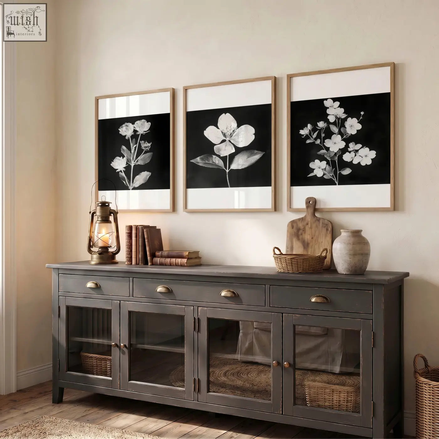 Dark gray wooden sideboard with glass paneled doors and brass handles next to black framed picture set of 3 botanical prints