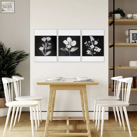 Set of 3 black framed french country botanical wall art prints in black and white above wooden dining room table