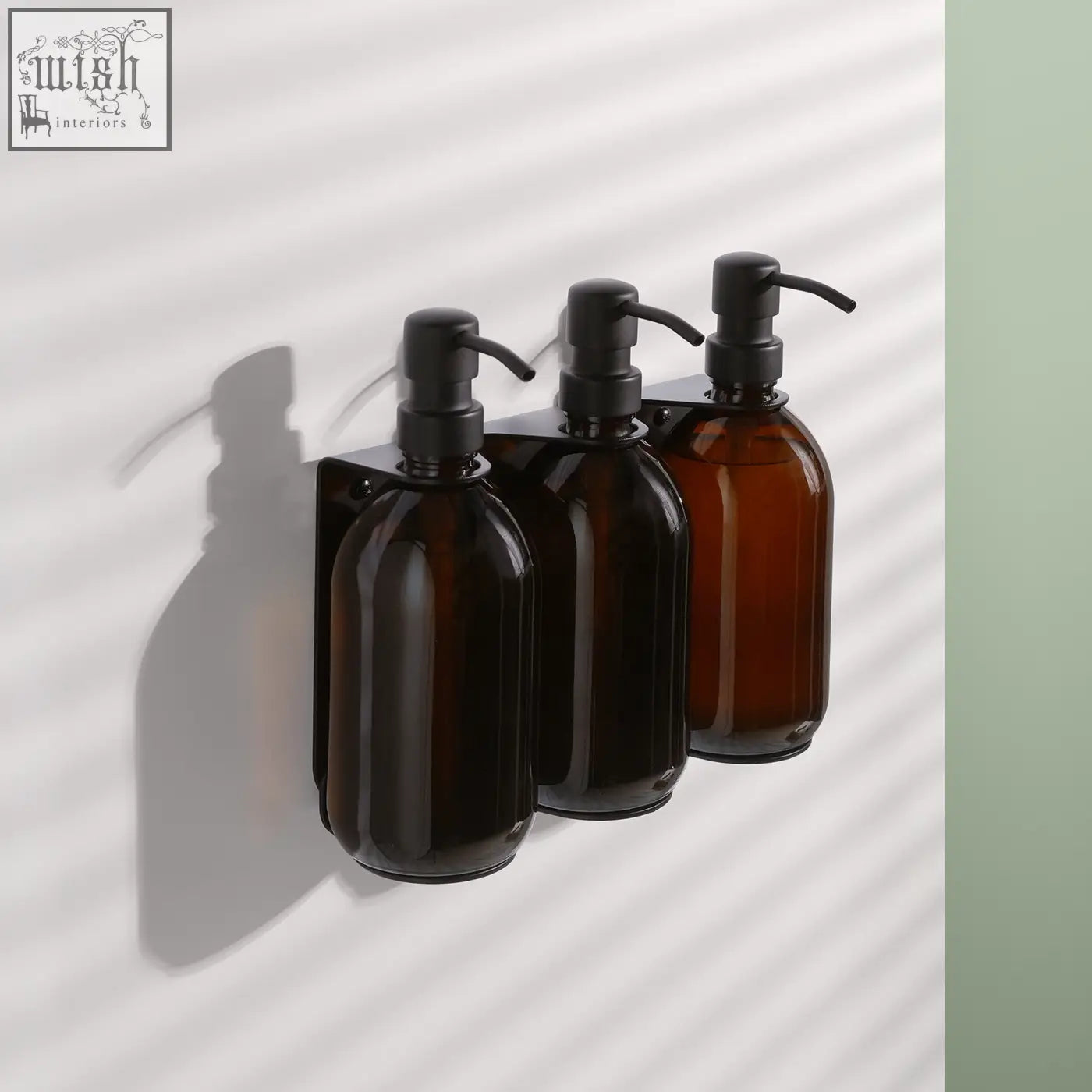 Black triple wall-mounted soap dispenser set with amber glass bottles and black pump heads on a wall bracket