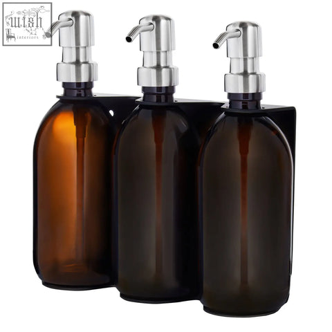 Black triple wall-mounted soap dispenser set with amber glass bottles and stainless steel pumps on a black bracket