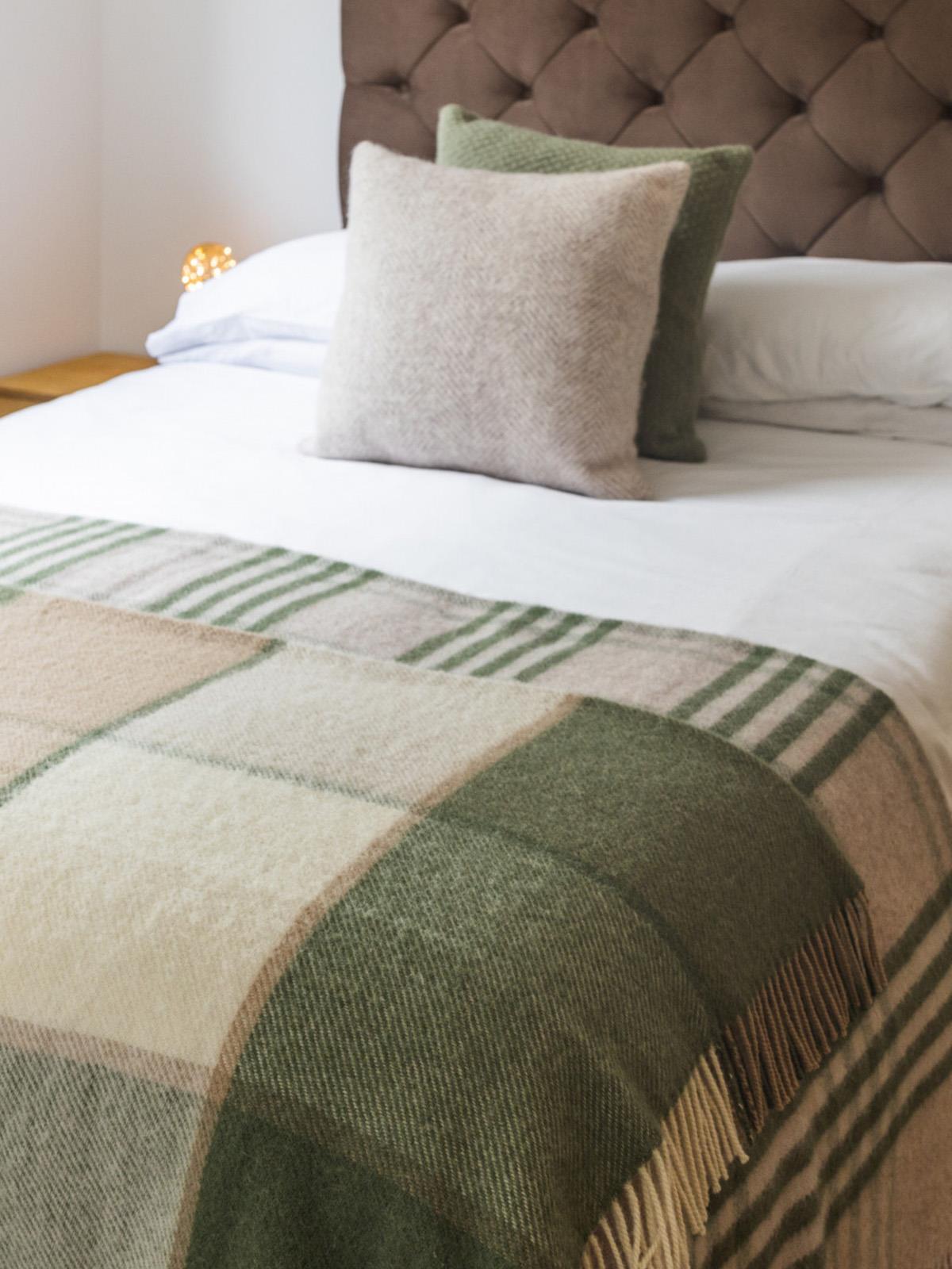 A cozy block check pure new wool throw in olive with earth tones, fringed edges, and a soft textured weave
