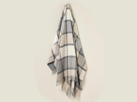 A soft cream and gray windowpane block check throw blanket made from merino lambswool with fringed edges
