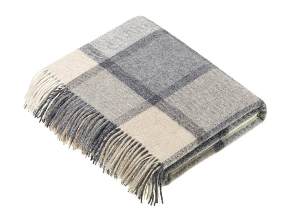 A soft folded merino lambswool throw with a windowpane block check pattern in white and grey and fringe edges