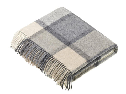 A soft folded merino lambswool throw with a windowpane block check pattern in white and grey and fringe edges