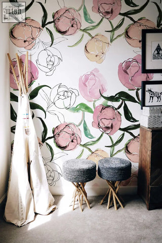 Two dark gray woven stools with light wood legs against pale blooming peonies removable wallpaper for living space