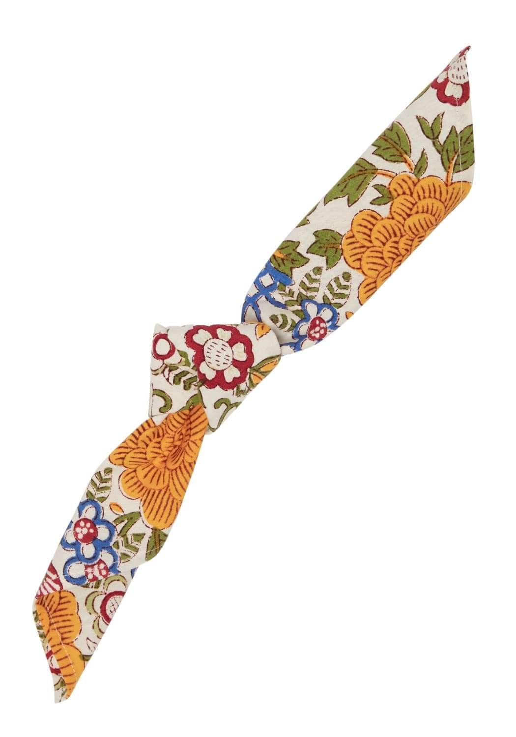 A cream fabric headband with vibrant orange red blue and green floral fruit print from blooming spring napkin set