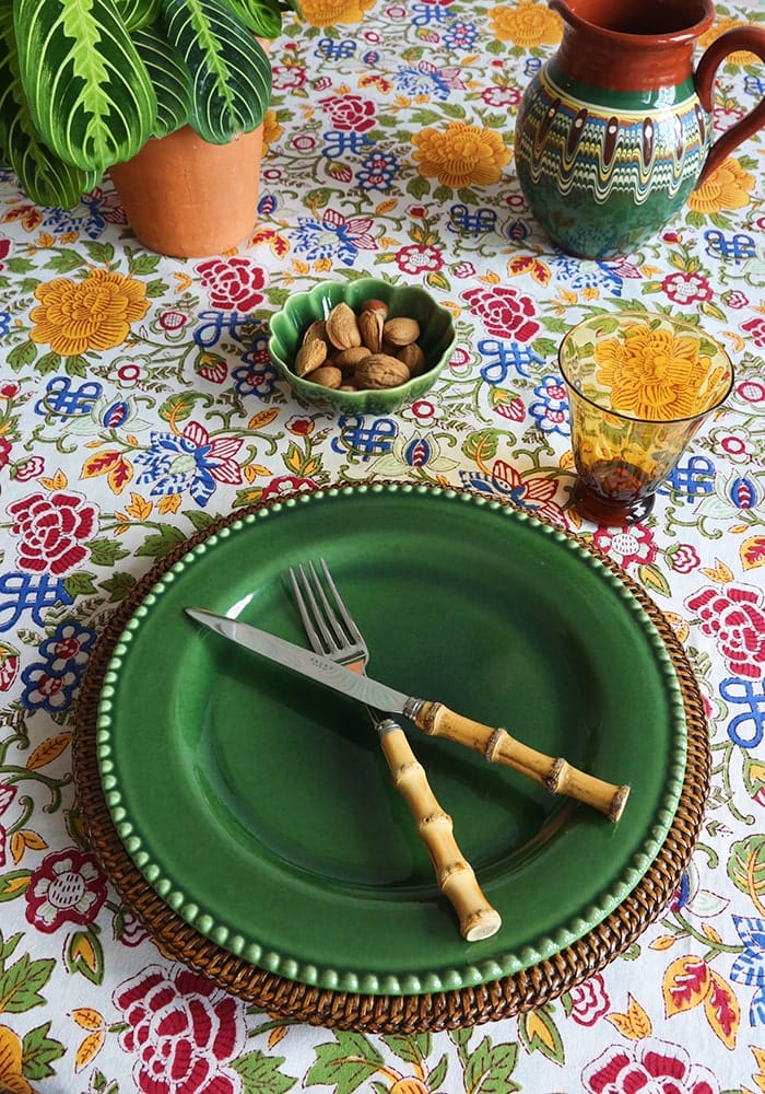 Green ceramic plate with beaded rim on woven placemat showcasing blooming spring tablecloth style