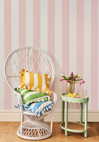 White wicker peacock chair with blue and white cabana striped ruffled cushion cover and colorful striped cushions