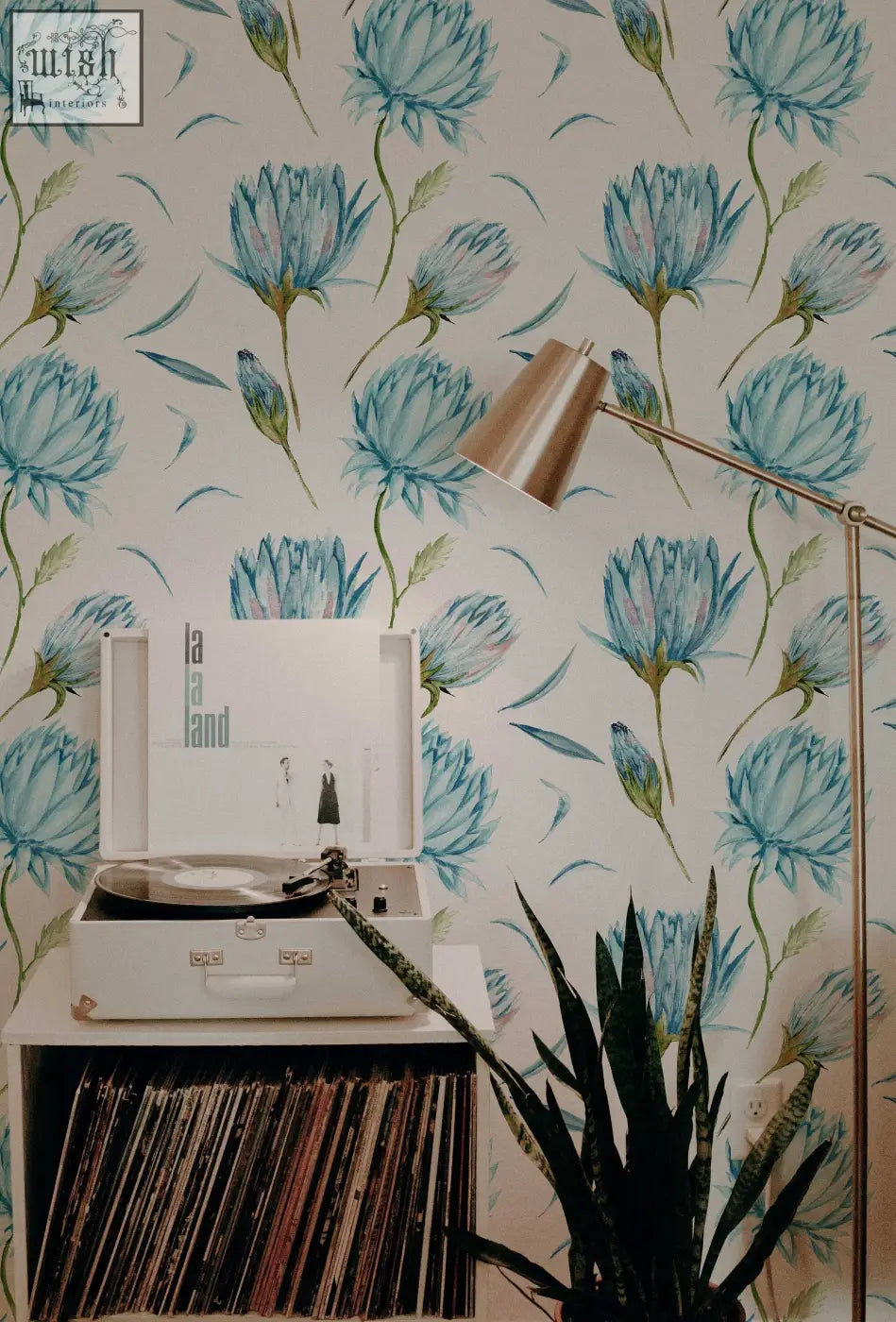 White vintage-style record player with silver turntable beside blue flowers wallpaper and green leaves peel and stick decor