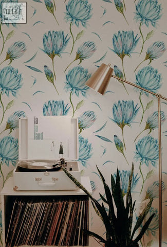White vintage-style record player with silver turntable beside blue flowers wallpaper and green leaves peel and stick decor
