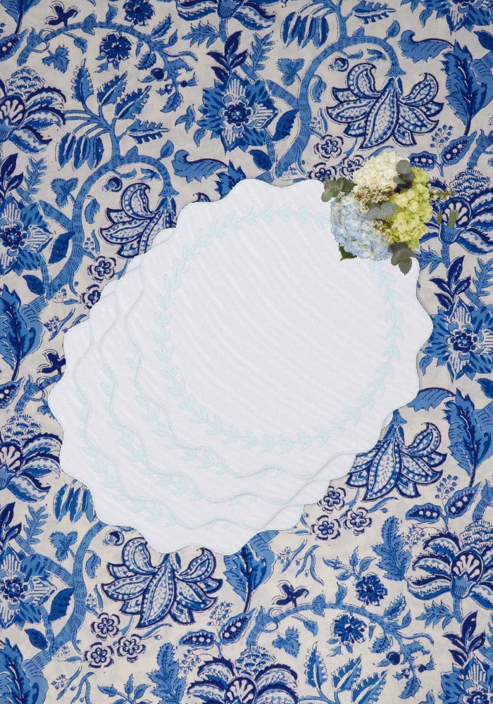 White scalloped plate on intricate blue and cream floral fabric showcasing blue garland placemats set of 4