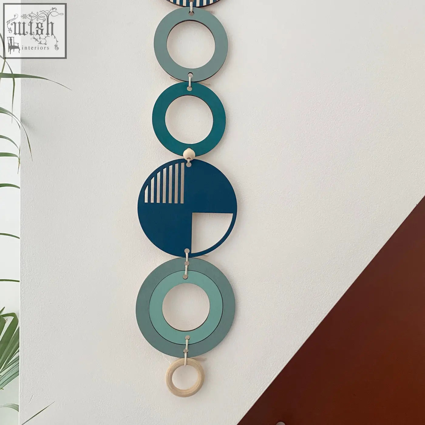 Blue modern wall art featuring stacked teal and blue discs with cut-out designs and a natural wood ring for wall decor