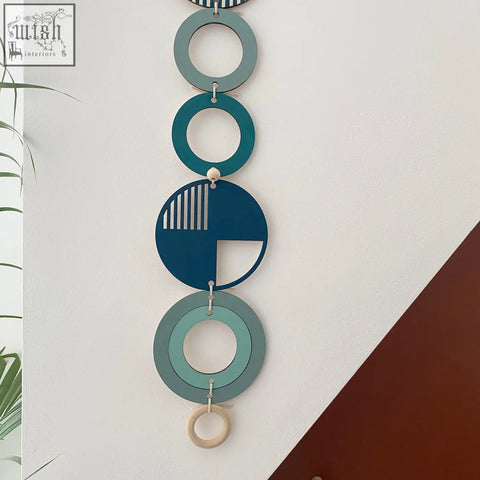 Blue modern wall art featuring stacked teal and blue discs with cut-out designs and a natural wood ring for wall decor