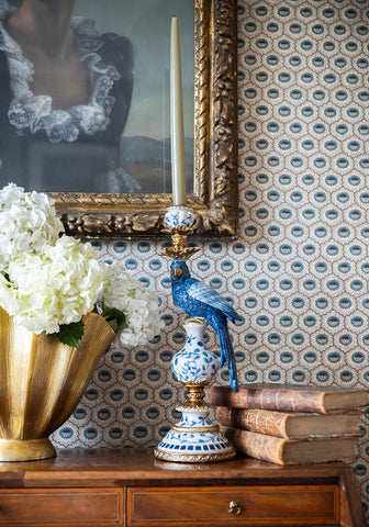 Blue parrot decorative tall candle holder with intricate white floral patterns on blue ceramic and gold-toned base