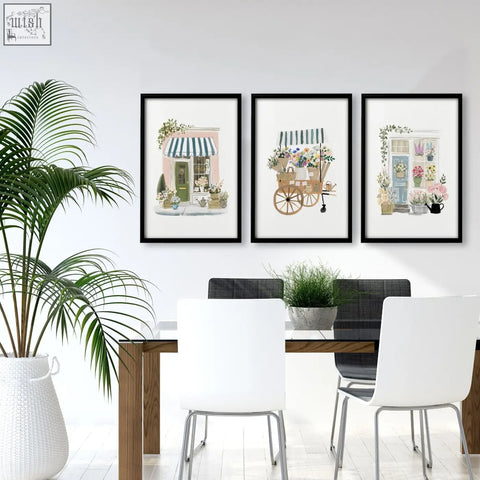 Three blue framed floral shop prints hang as wall art above a dining room table for a flower shop vibe