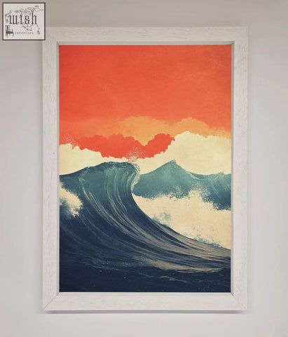 A framed poster of blue waves crash under a red sunset in a white distressed frame perfect for wall decor