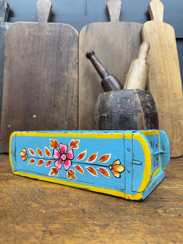 A vibrant turquoise wooden painted brick mould with yellow trim and colorful floral designs for herb planting or storage