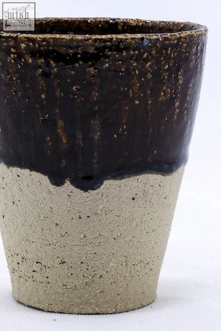 A rustic bluvio quadra milled tall ceramic cup with dark brown speckled glaze dripping over textured beige base