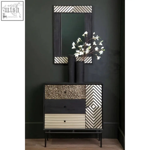 Boho black wall mirror shown above a black and cream geometric-patterned console table with textured drawer fronts