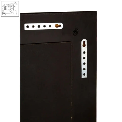 Boho black wall mirror featuring a black wooden frame with white metal hardware and a brass knob on a black wall