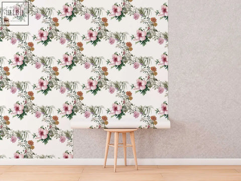 A roll of boho floral wallpaper with pink hibiscus flowers green leaves and orange accents on cream for living space