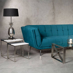 Teal tufted sofa with metallic legs next to a boho nickel finish pineapple table lamp on a side table