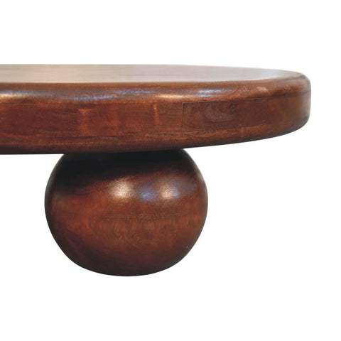A dark brown polished wooden bola coffee table with a round top and a spherical pedestal base