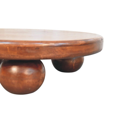 Round wooden bola coffee table with smooth polished surface and three rounded ball feet for stylish living rooms