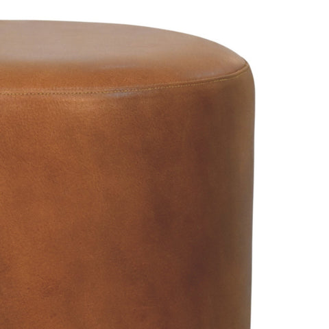Tan leather cylindrical bola leather stool with smooth textured surface and visible stitching along curved edge